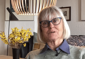 Anne Marie MS_1157_Crop_web Kvinde taler til kameraet imens hun sidder i sofa.